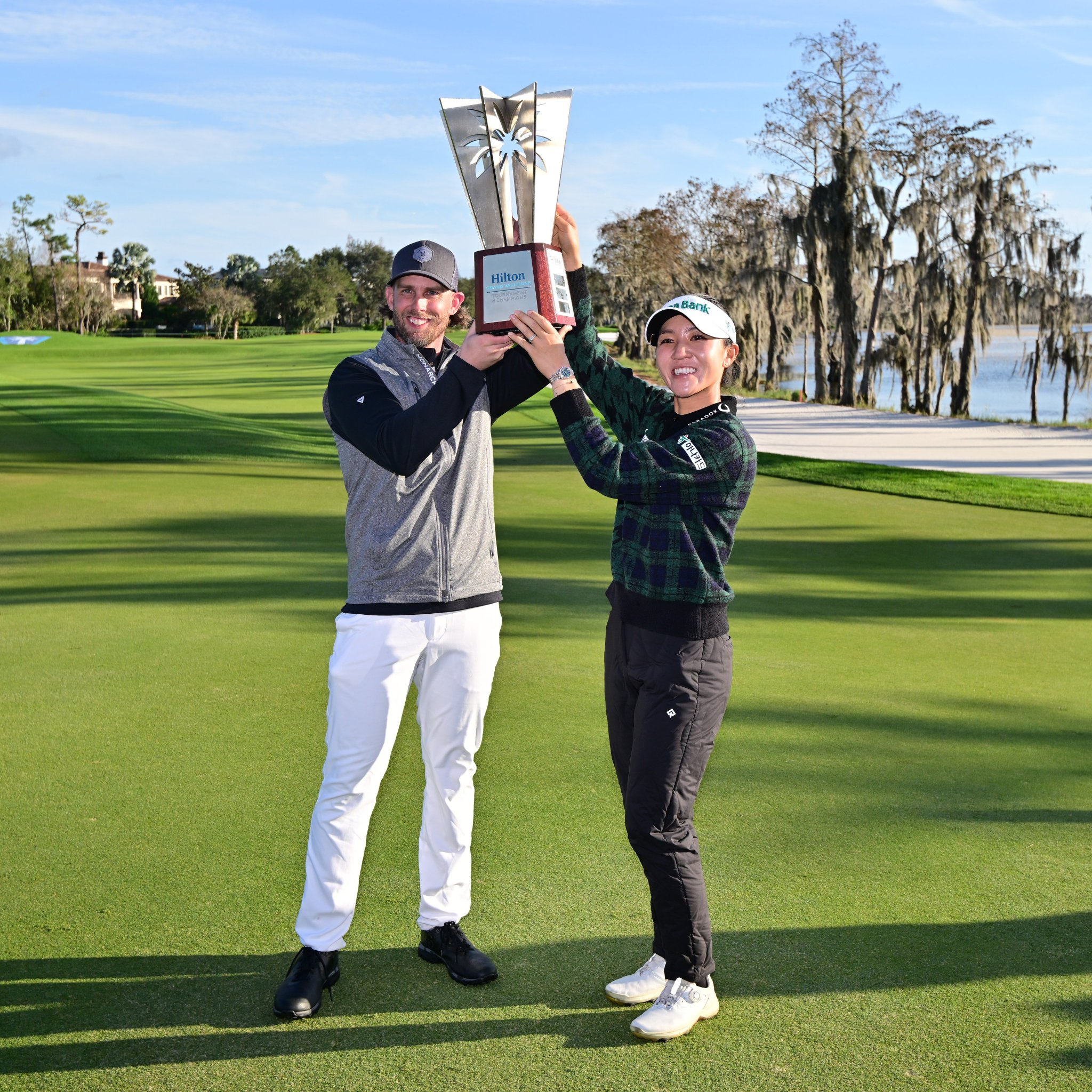 Jeff McNeil and Lydia Ko holding Hilton Grand Vacations TOC trophy made by Malcolm DeMille